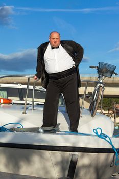 Overweight man in tuxedo standing on the deck of a luxury pleasure boat