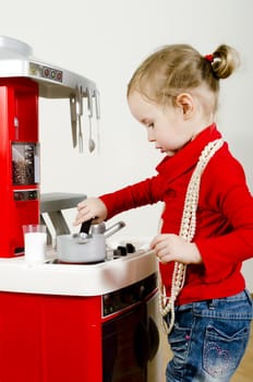 Little cute girl playing in children's kitchen.
