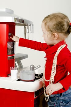 Little cute girl playing in children's kitchen.