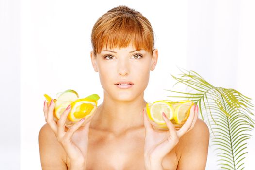 Portrait of a pretty brunette girl with two bowl full of fruit in her hands in a spa salon