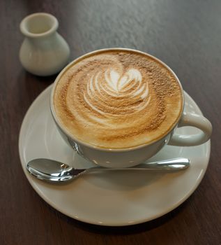 White Ceramic Cup of Coffee with Small Silver spoon on Wood table