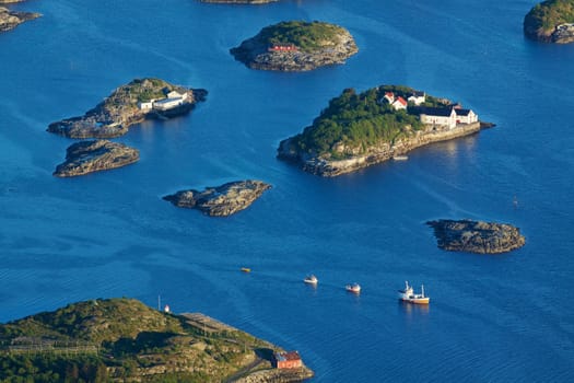 Bird eye view of fishing boats sailing between scenic islets near Henningsvaer on Lofoten islands in Norway