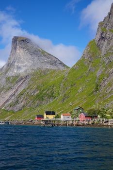 Scenic fishing village of Rostad on Lofoten in Norway with mountain peaks towering above the fjord