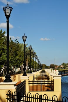 A row of lamp osts along a walkway overlooking a man-made lake.