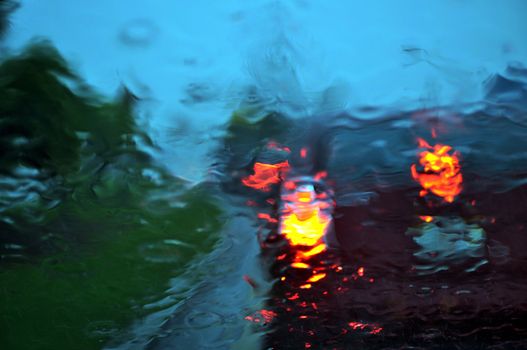 Wet car windshield in traffic during a rain storm. 