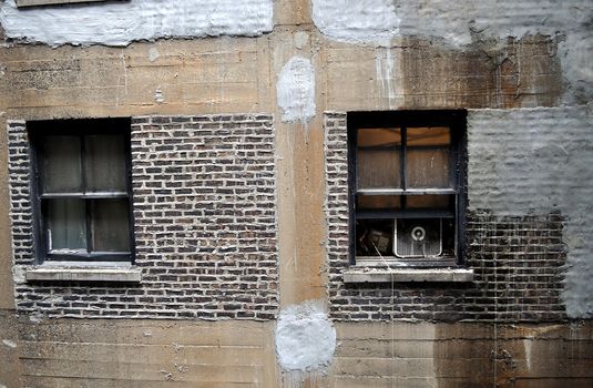 Two windows in an old, rundown apartment building.