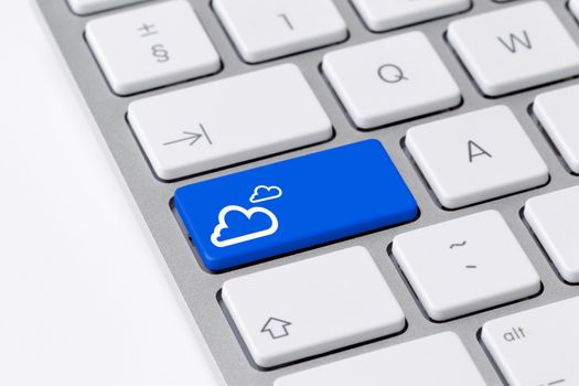 Photo of a computer keyboard with one blue button with cloud icon symbolising cloud computing, social media connection and data storage.