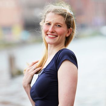 Happy joyful middle-aged woman with a lovely wide smile standing outdoors in a breeze 