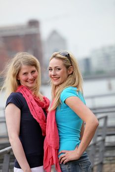 Two attractive smiling blonde women standing close together having an intimate chat 