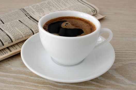 A cup of freshly brewed coffee on the table with newspaper