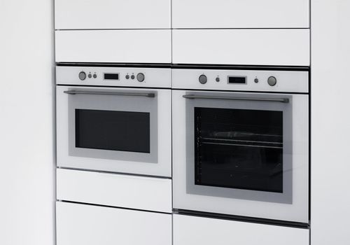 Modern ovens integrated in contemporary white kitchen