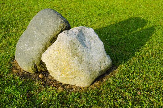 Two big stones in meadow surrounded with cut grass.
