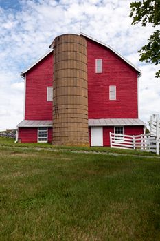 Red painted wooden barn with white door on farm in traditional US style