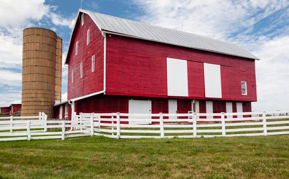 Red painted wooden barn with white door on farm in traditional US style