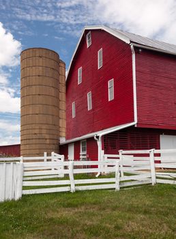 Red painted wooden barn with white door on farm in traditional US style