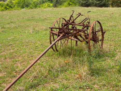 Rusted farm plow or plough pulled by horse in a field on farm