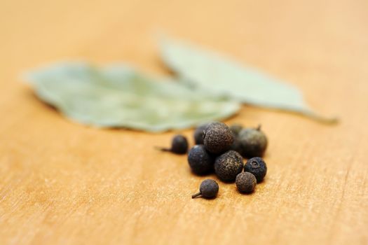 An image of pepper and bay on wooden table
