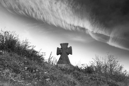An black and white image of old cross in a graveyard