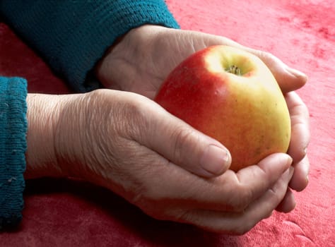 An image of old hands with an apple