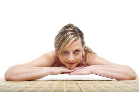 Matured naked woman lying on mattress, all prepared for spa care