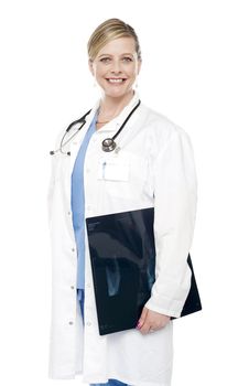 Smiling female surgeon carrying x-ray report along with her, dressed in uniform