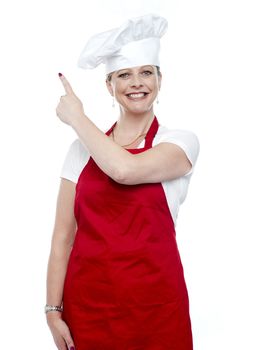 Smiling female cook pointing away. Representing copy space area