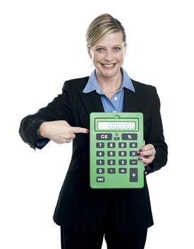 Cheerful woman pointing at big green calculator isolated over white