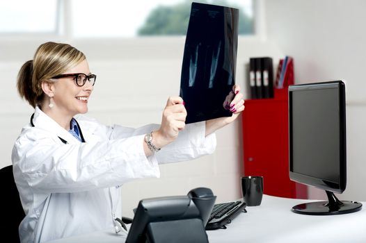 Female doctor looking at x-ray report of patient in clinic. Its good news, she is smiling