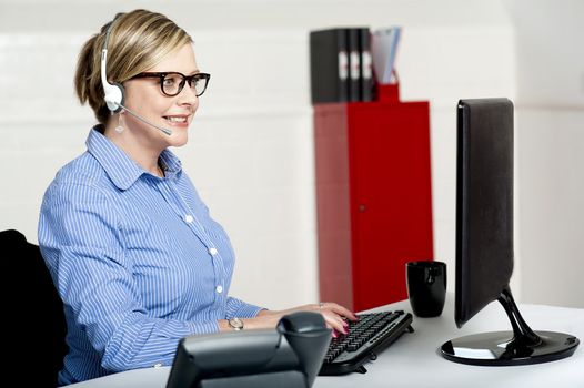 Female executive taking instructions from clients over a call and feeding same on computer