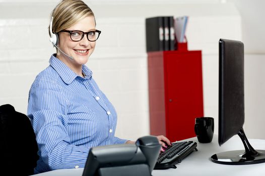 Smiling senior woman sitting in front of computer and working