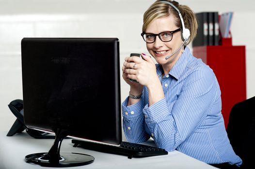 Aged businesswoman sipping coffee during break. At work desk