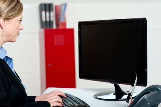 Female executive typing and looking at lcd screen. Working on computer