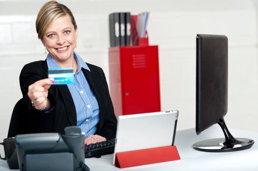 Beautiful corporate woman holding credit card and showing it to camera