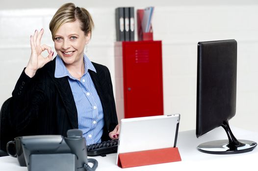 Senior female executive showing excellent gesture while sitting at work desk