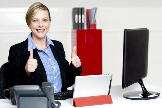 Senior businesswoman gesturing thumbs up working actively in office