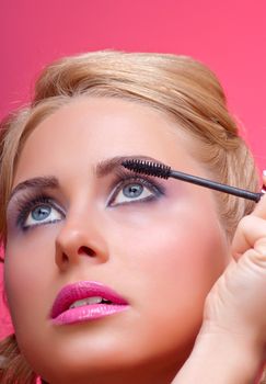 Beautiful woman applying mascara on her eyelashes