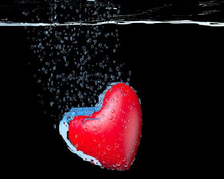 heart dropped into water over black background