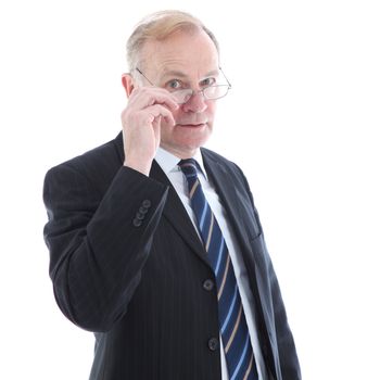 Judgemental elderly business executive peering over the top of his glasses with a serious watchful expression 