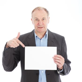 Middle-aged businessman pointing to a blank white card or sign that he is holding with copyspace for your text 