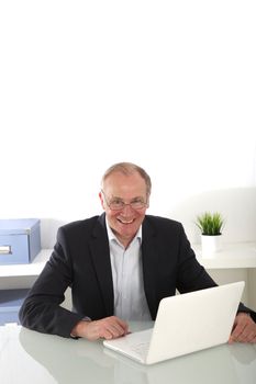 High angle view of a smiling senior businessman seated at his desk with copyspace 