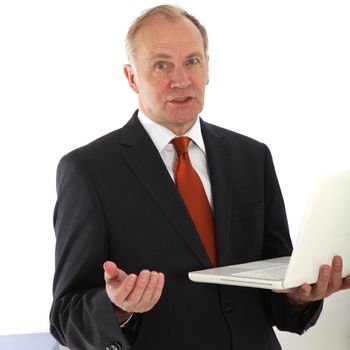 Persuasive businessman talking and gesturing to the camera holding an open laptop balanced on his arm 