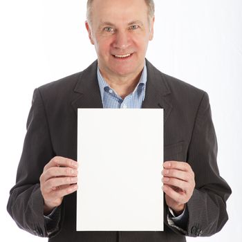 Friendly smiling middle-aged businessman holding blank white card in front of his chest for your text isolated on white 