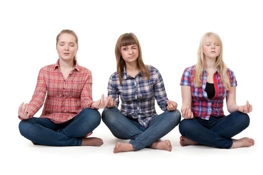 Three girls sitting in lotus posture on a white background