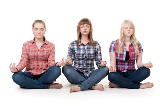 Three girls sitting in lotus posture on a white background