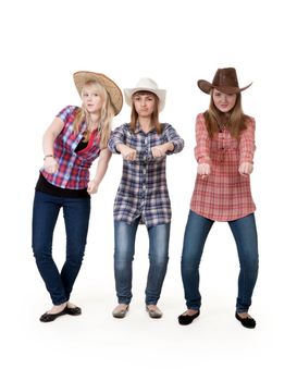 Three girls in hats imitate horse riding on a white background