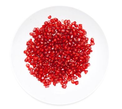 Red pomegranate seeds on a plate on a white background