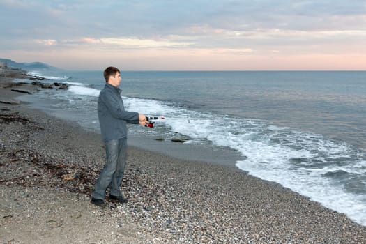 fisherman on the shore of evening sea