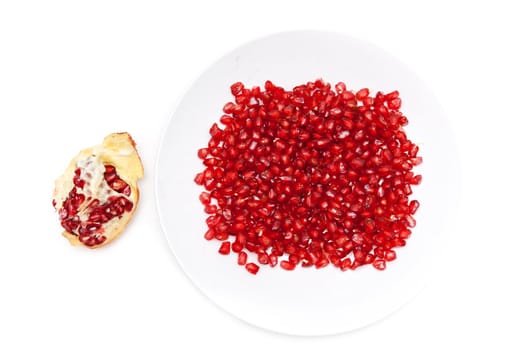 Red pomegranate seeds on a plate, and peeled fruit
