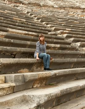 Girl with a striped dress sitting in the amphitheater