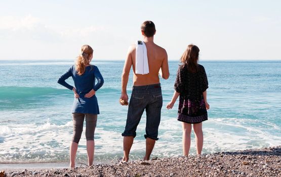 man and two girls looking at the sea